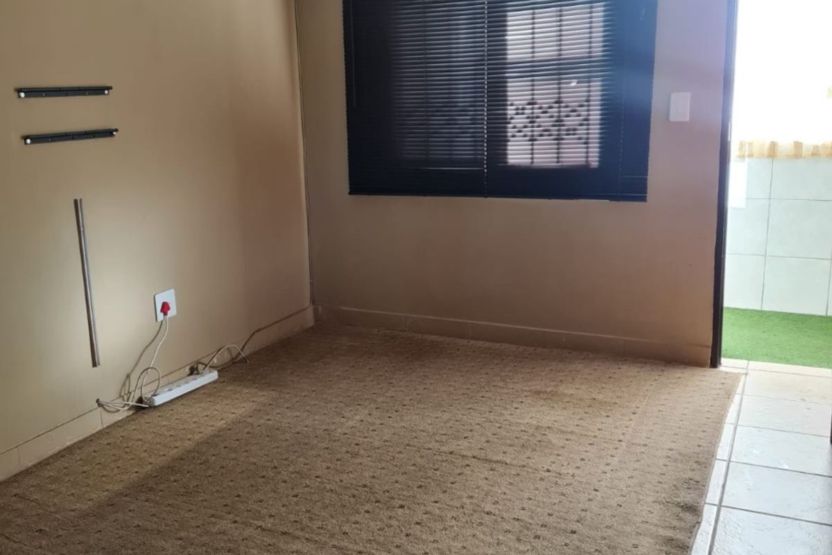 An empty living room featuring carpeted flooring, a split-system air conditioner, and direct access to an outdoor balcony area.