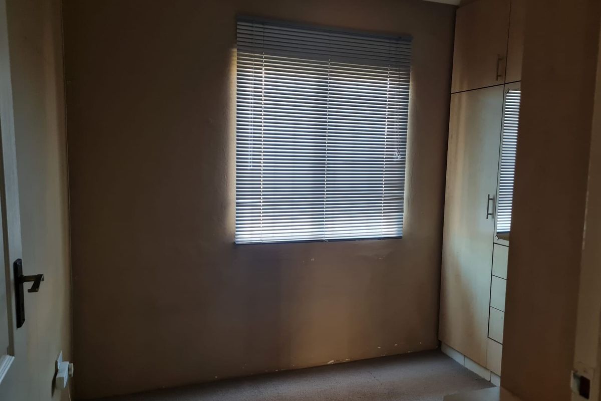 A vacant bedroom featuring built-in cupboards, carpeted flooring, and venetian blinds, offering a neutral space ready for personalization.