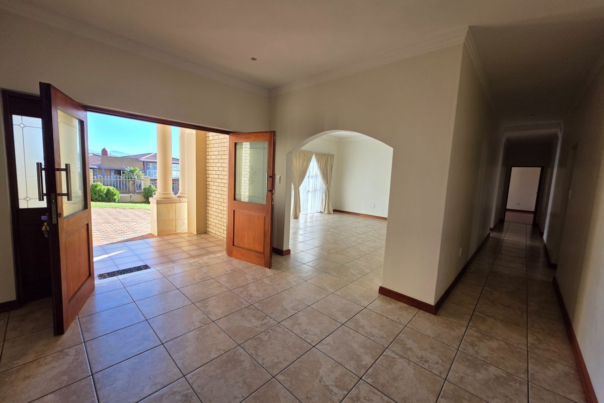 Spacious, light-filled living area featuring neutral tiled flooring, an elegant archway, and double doors opening onto an outdoor patio space.