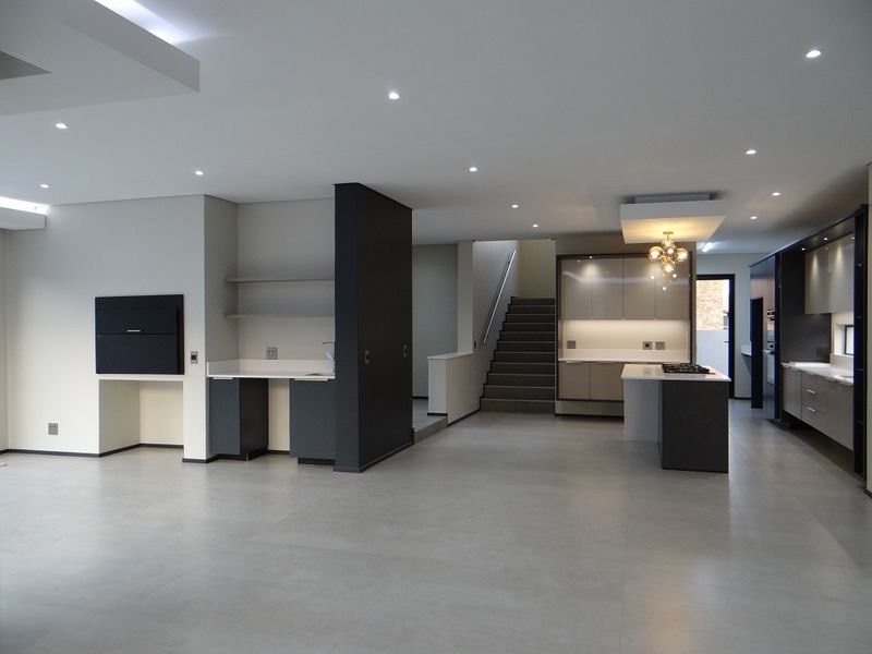 Spacious open-plan living area featuring a modern kitchen with built-in cabinetry, a central island, and a sleek staircase leading to the upper level.