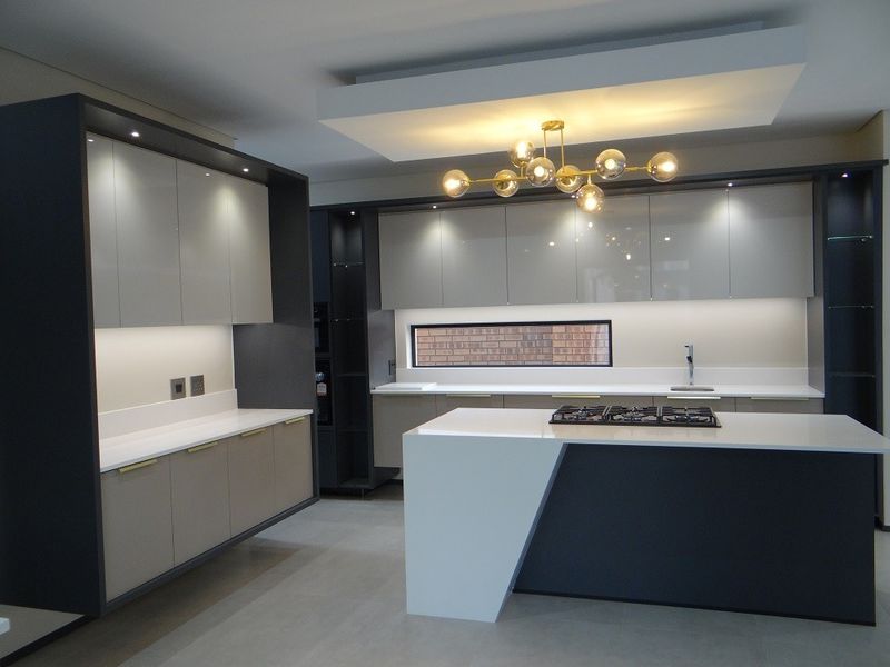 Modern, high-end kitchen featuring sleek built-in cabinetry, a large central island with a gas hob, stone countertops, and sophisticated recessed lighting.