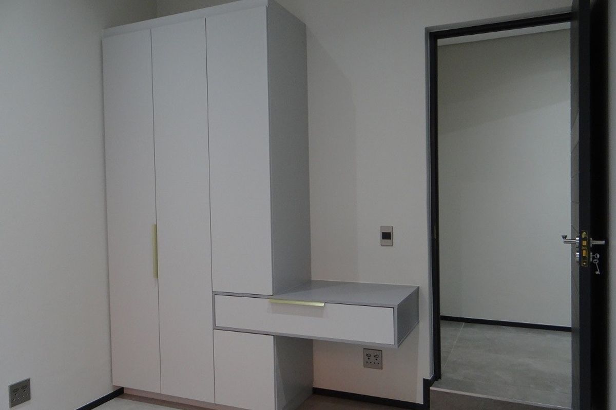 A modern bedroom featuring a sleek built-in wardrobe with an integrated vanity desk, neutral finishes, and clean architectural lines.