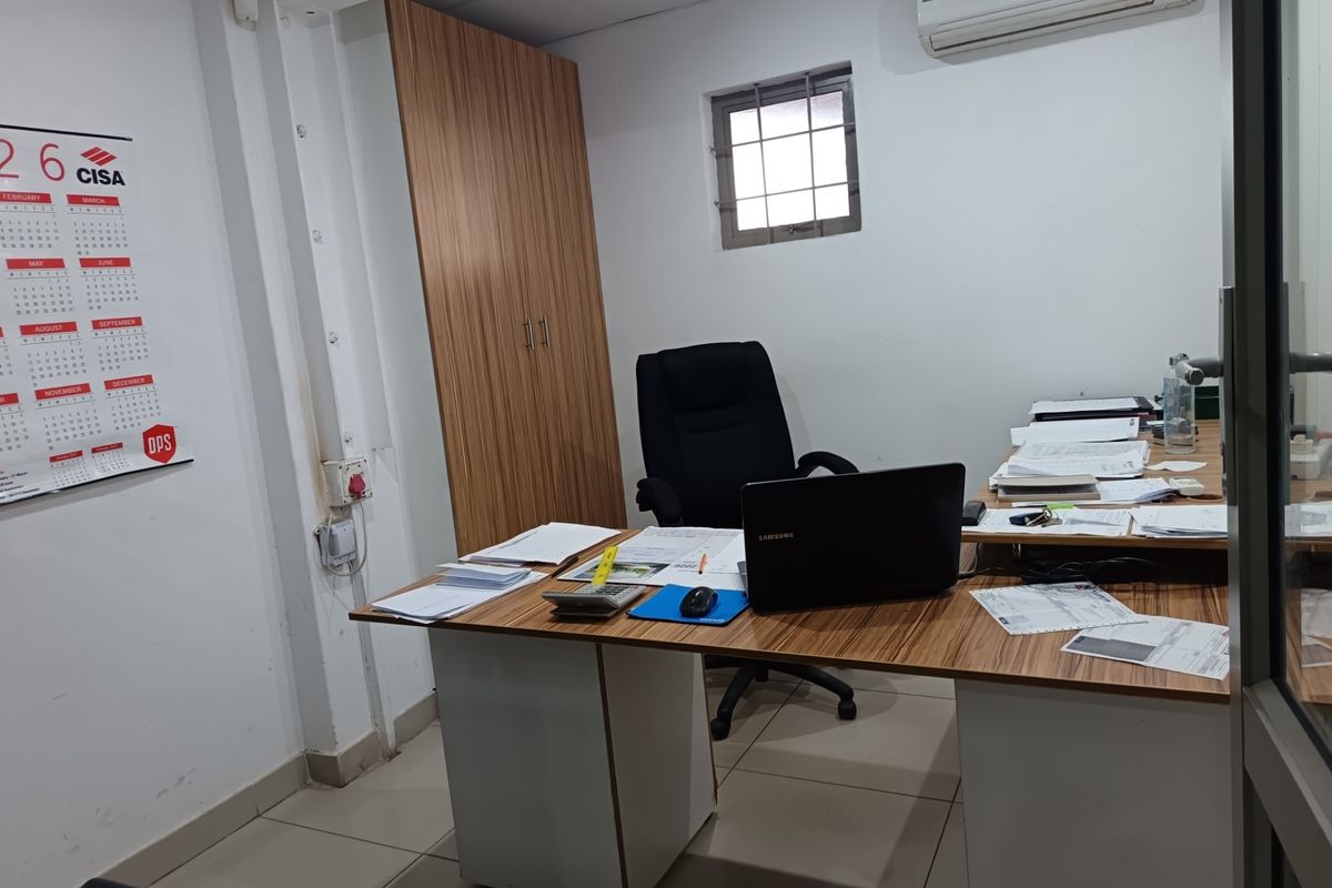 A functional office space featuring tiled flooring, a built-in storage cupboard, and a wall-mounted air conditioning unit.