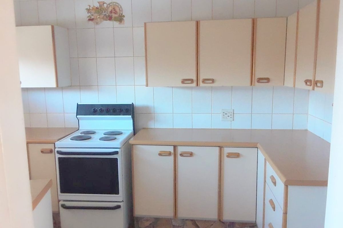 A functional kitchen featuring laminate countertops, built-in cabinetry, a tiled backsplash, and a freestanding electric stove.