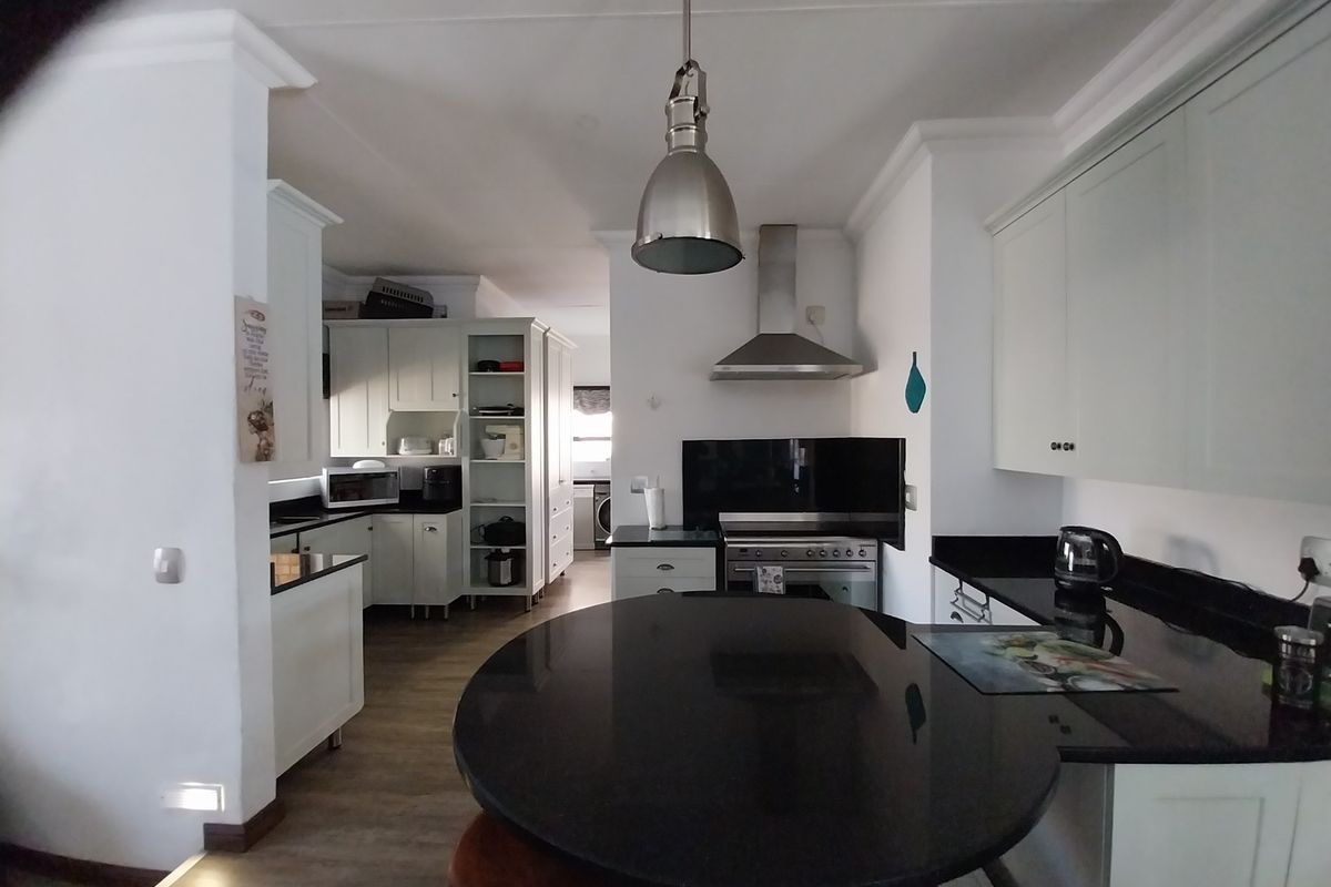 A well-appointed kitchen featuring granite countertops, ample built-in cabinetry, a stainless steel oven with extractor fan, and a central breakfast nook.