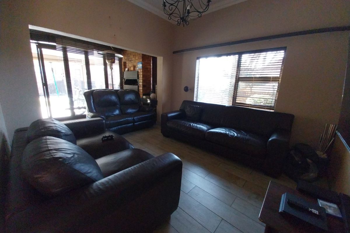 Spacious living room featuring tiled flooring, exposed brick fireplace, and large sliding glass doors providing natural light and access to the outdoor area.