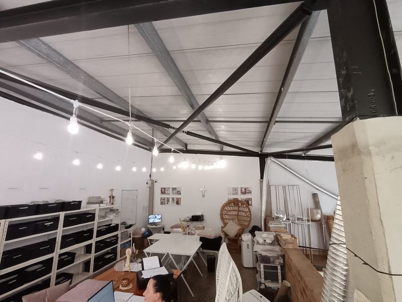 Open-plan commercial office space featuring exposed steel roof trusses, industrial ceiling structure, and functional lighting, suitable for a creative or collaborative workspace.