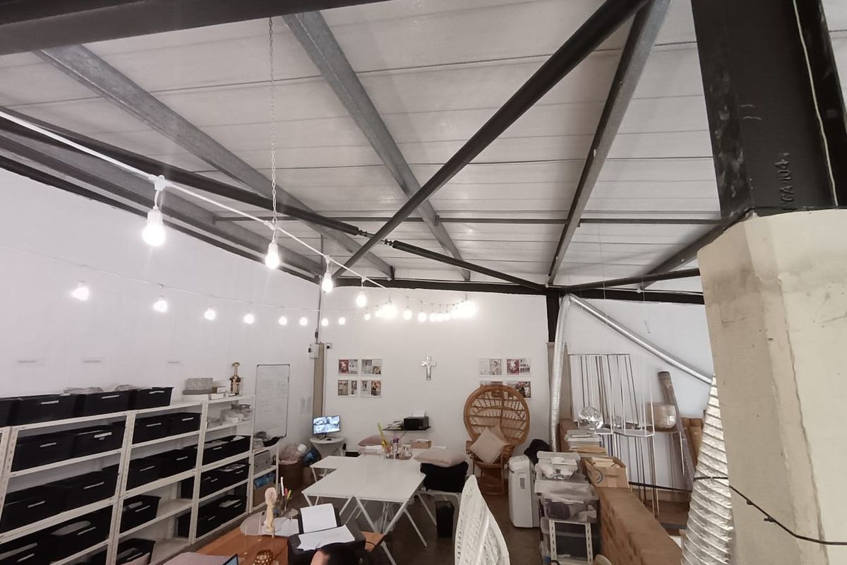 Open-plan commercial office space featuring exposed steel roof trusses, industrial ceiling structure, and functional lighting, suitable for a creative or collaborative workspace.