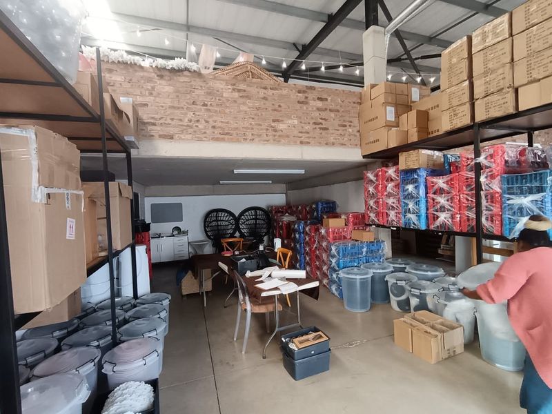 A functional commercial utility or storage space featuring high ceilings with exposed steel trusses, a mezzanine level, and durable concrete flooring.