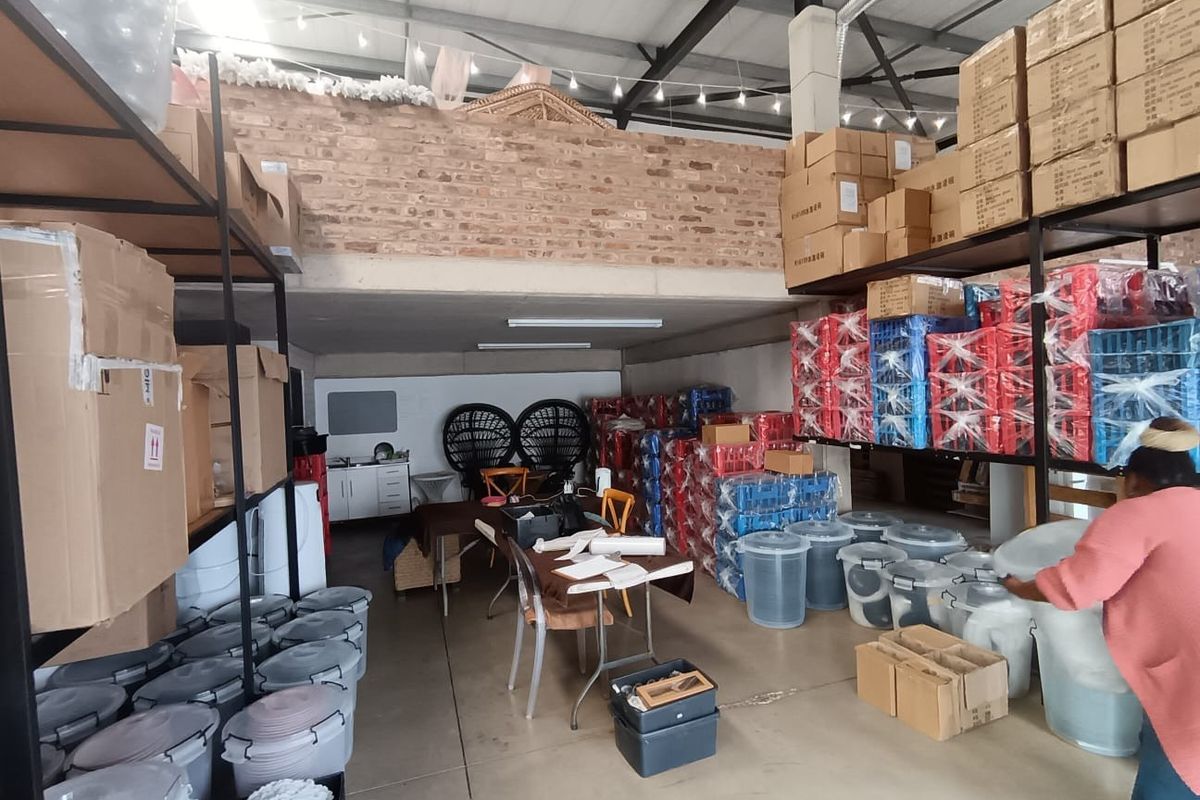 A functional commercial utility or storage space featuring high ceilings with exposed steel trusses, a mezzanine level, and durable concrete flooring.