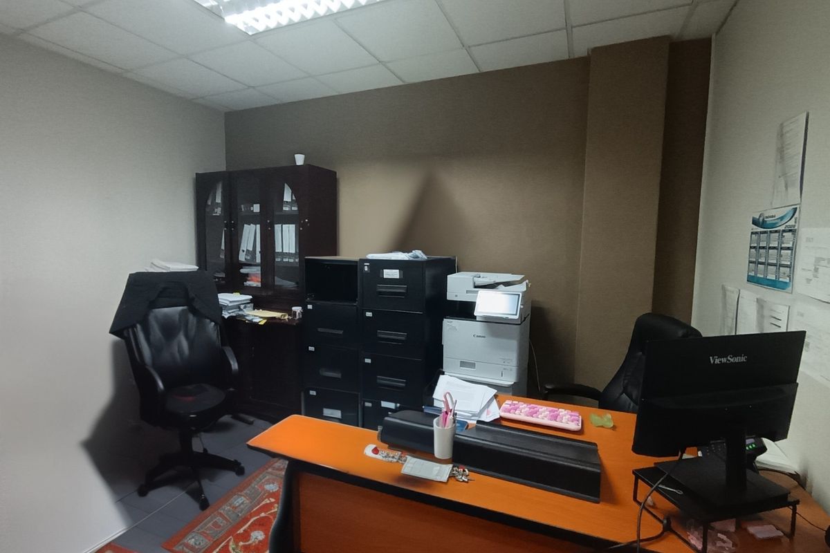 A functional office space featuring a suspended ceiling with integrated fluorescent lighting, providing a practical work environment.