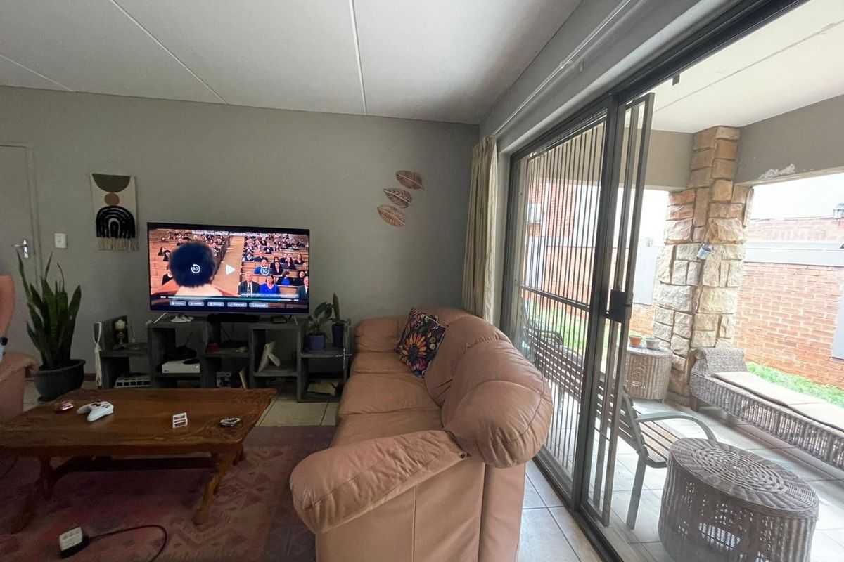 A living room featuring tiled flooring and large sliding glass doors that provide access to a covered patio area.