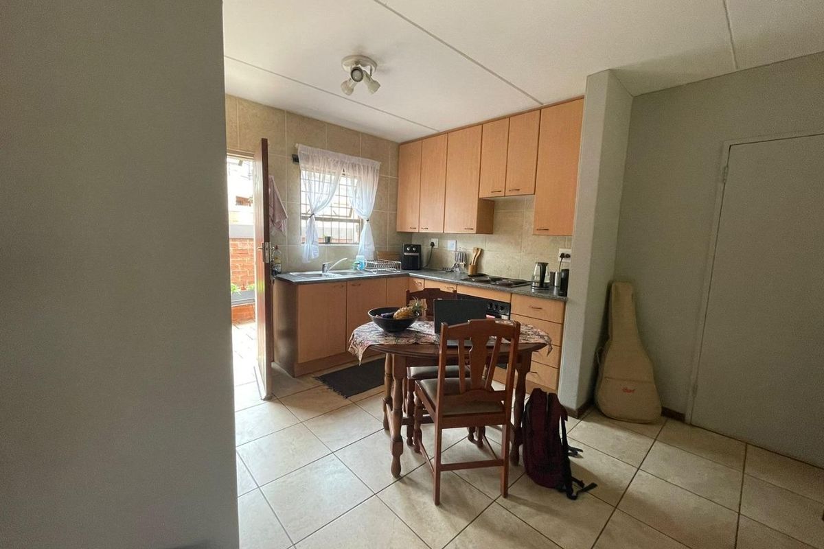 A functional kitchen featuring laminate cabinetry, tiled backsplash, and ceramic flooring, with direct access to an outdoor area.