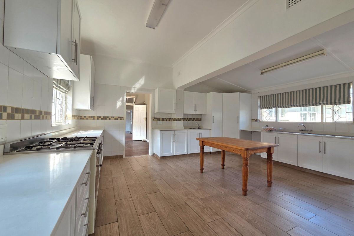 Spacious kitchen featuring white cabinetry, gas cooktop, tiled splashback, and wood-look floor tiles, offering a functional layout with ample counter space.