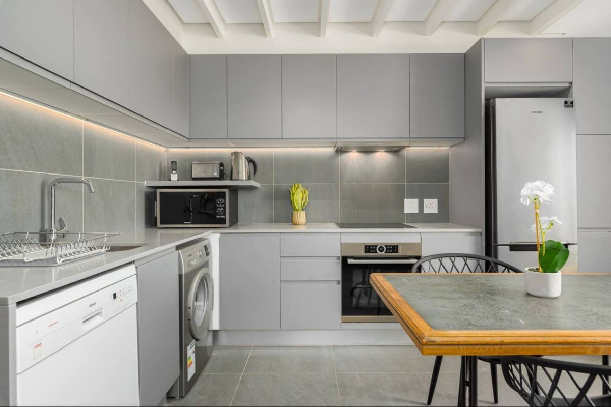 Modern, well-appointed kitchen featuring sleek grey cabinetry, stone countertops, integrated appliances, and stylish under-cabinet lighting for a clean, contemporary aesthetic.
