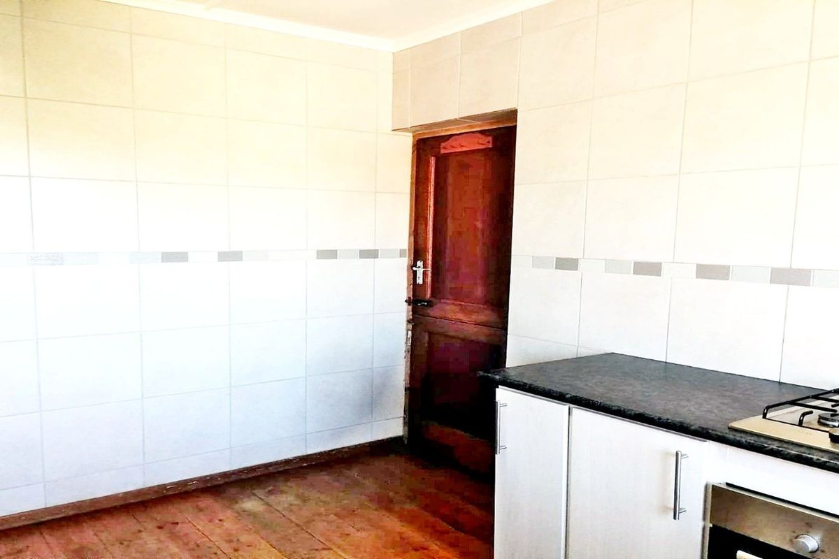 A functional kitchen space featuring tiled walls, built-in cabinetry with a gas hob and oven, and timber flooring.