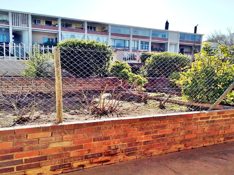 A garden area featuring a brick retaining wall and chain link fencing, providing a clear boundary for the outdoor space.