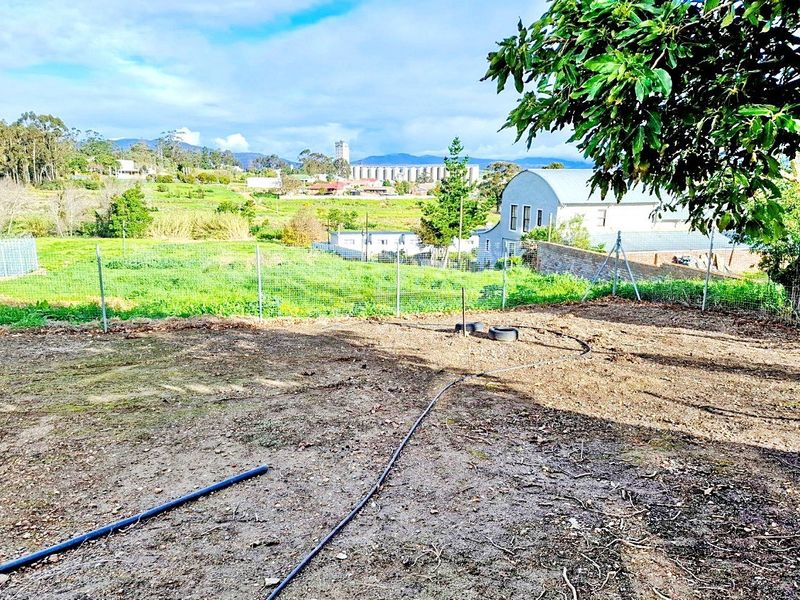 An undeveloped garden area featuring wire mesh fencing and irrigation piping, offering expansive views of the surrounding landscape and neighborhood.