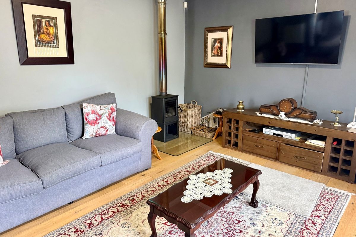 A comfortable living room featuring hardwood flooring and a built-in wood-burning fireplace with a stainless steel flue.
