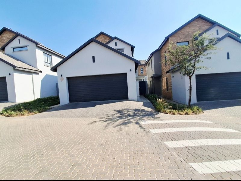 Modern residential property featuring a paved driveway, automated garage door, and contemporary brick and plaster facade.