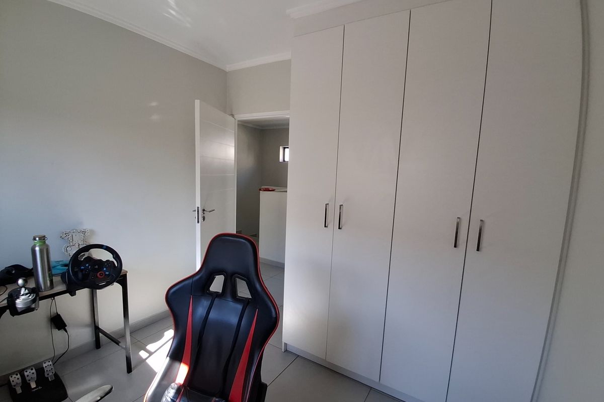 A bedroom featuring neutral walls, tiled flooring, and ample built-in cupboard storage space.