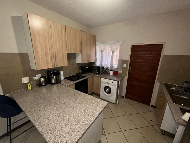 Functional kitchen featuring laminate cabinetry, granite-look countertops, built-in oven and hob, and a dedicated space for a washing machine.