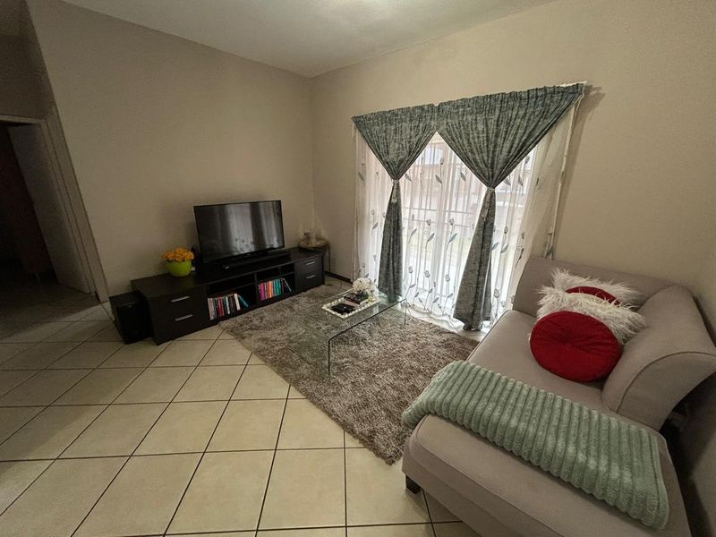 A comfortable living room featuring tiled flooring and a sliding glass door that provides natural light and access to the exterior.