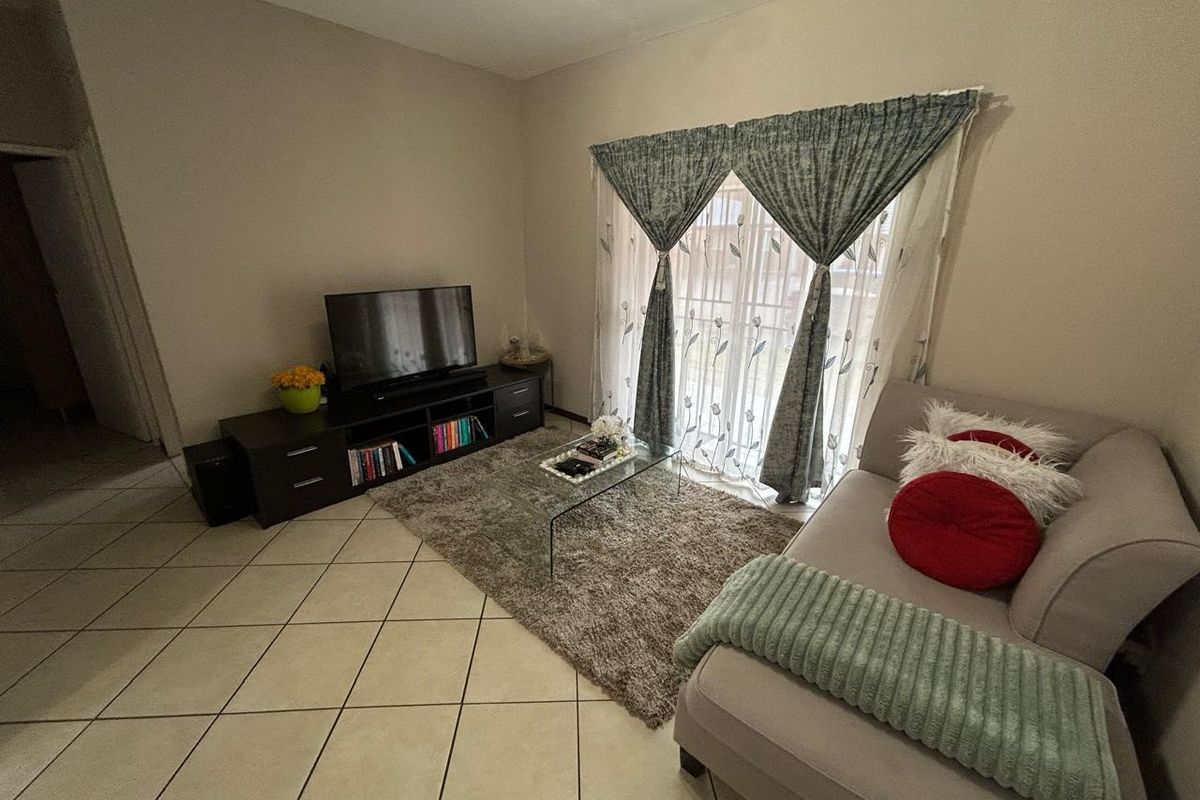 A comfortable living room featuring tiled flooring and a sliding glass door that provides natural light and access to the exterior.