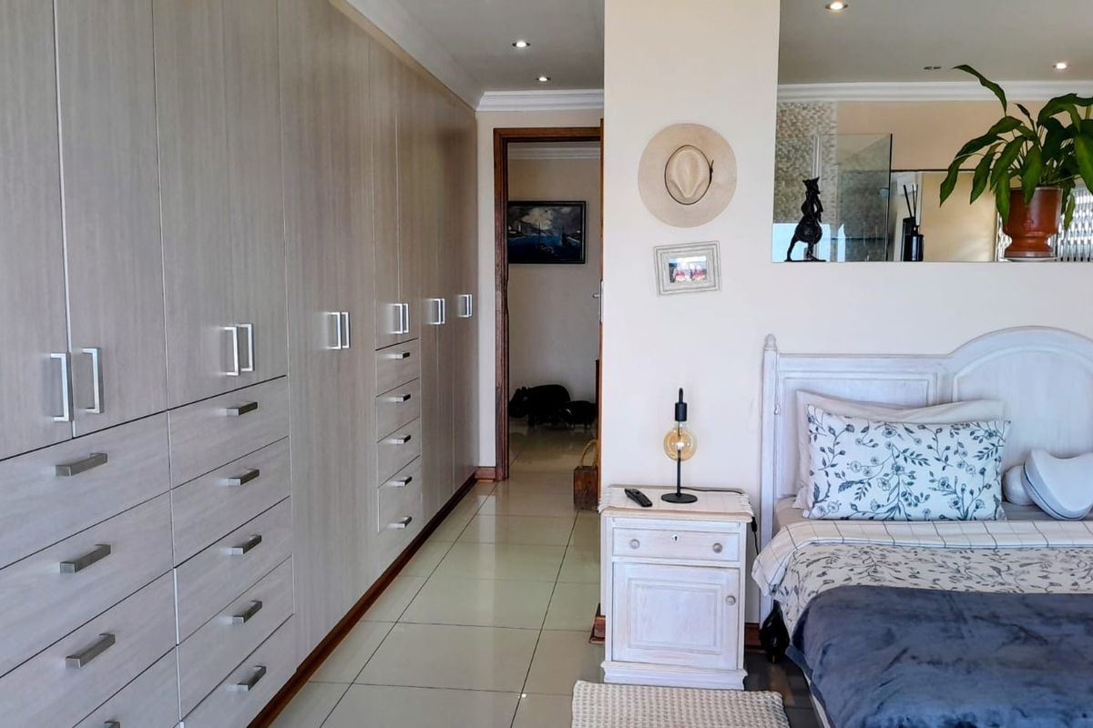 A well-maintained bedroom featuring extensive built-in cabinetry, neutral tiled flooring, and recessed ceiling lighting, offering a clean and functional living space.