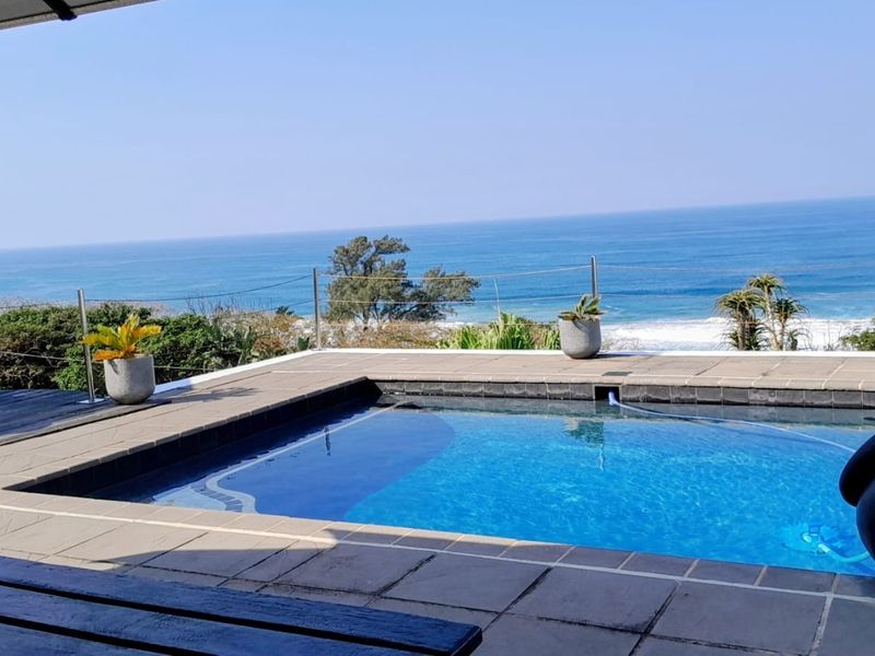 Outdoor pool area featuring a tiled surround, modern cable railing, and expansive ocean views.