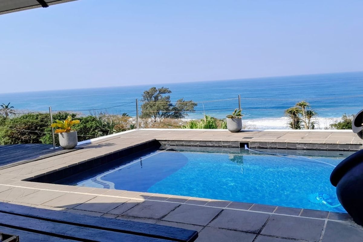 Outdoor pool area featuring a tiled surround, modern cable railing, and expansive ocean views.