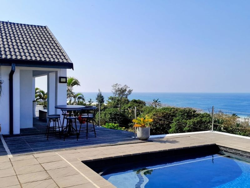 Outdoor pool area featuring a tiled swimming pool, timber decking, and modern balustrades with expansive ocean views.