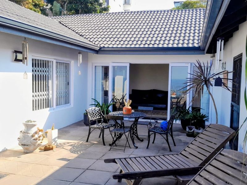 A paved outdoor patio area featuring sliding glass doors leading into the home, covered by a tiled roof structure.