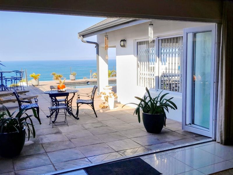 Covered patio area featuring tiled flooring and seamless access to the pool deck with expansive ocean views.