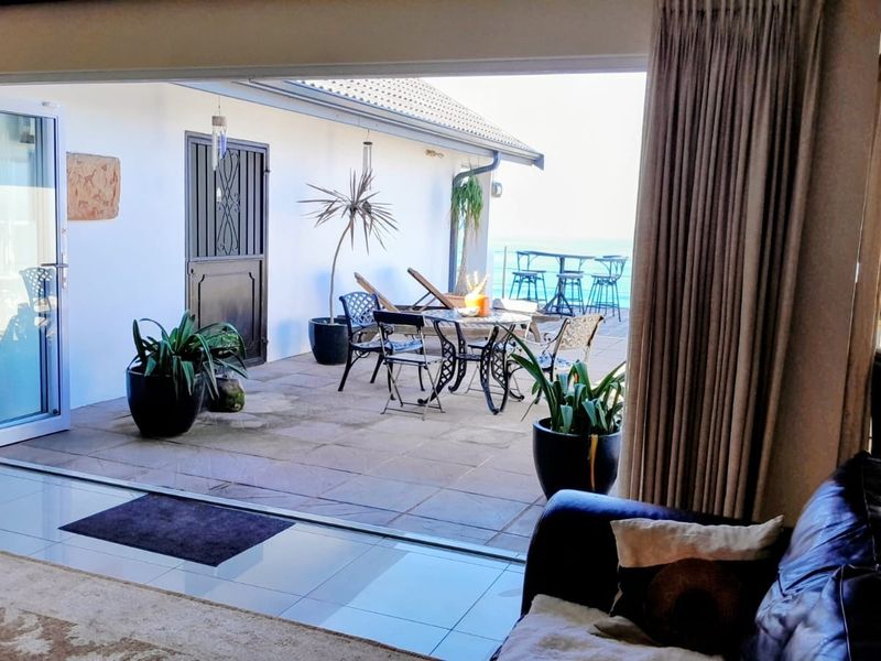 A covered outdoor patio area featuring tiled flooring and large sliding glass doors, providing seamless indoor-outdoor flow with ocean views.