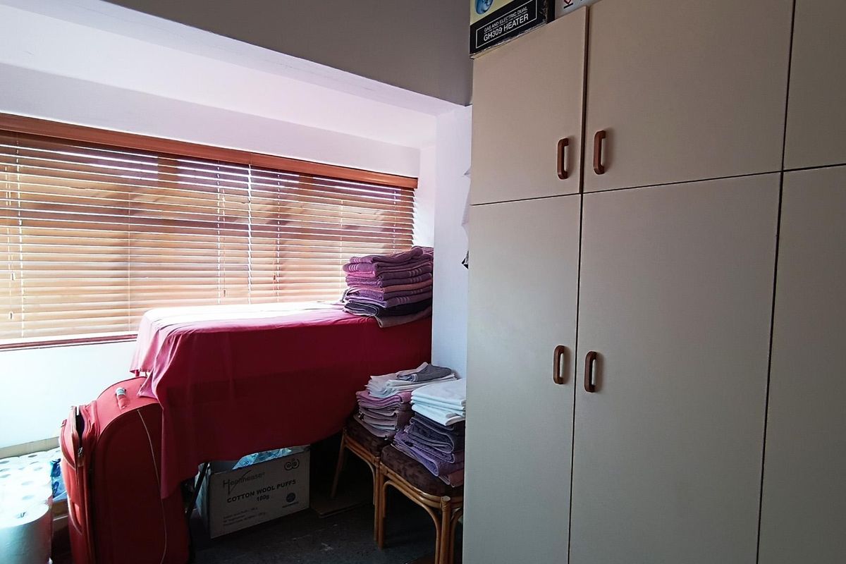 A bedroom featuring built-in cupboards and wooden venetian blinds, providing functional storage and adjustable natural light control.