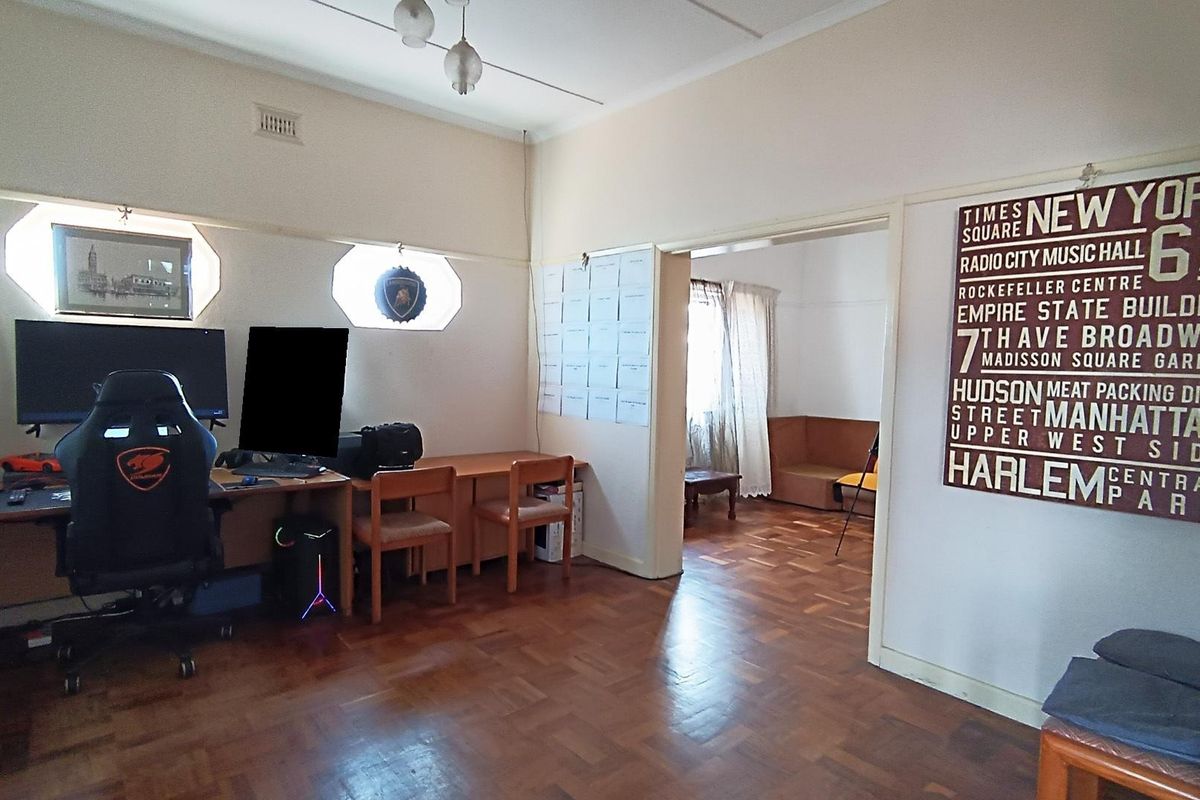 A living area featuring classic parquet flooring and unique octagonal windows, providing a versatile space with an adjoining room.