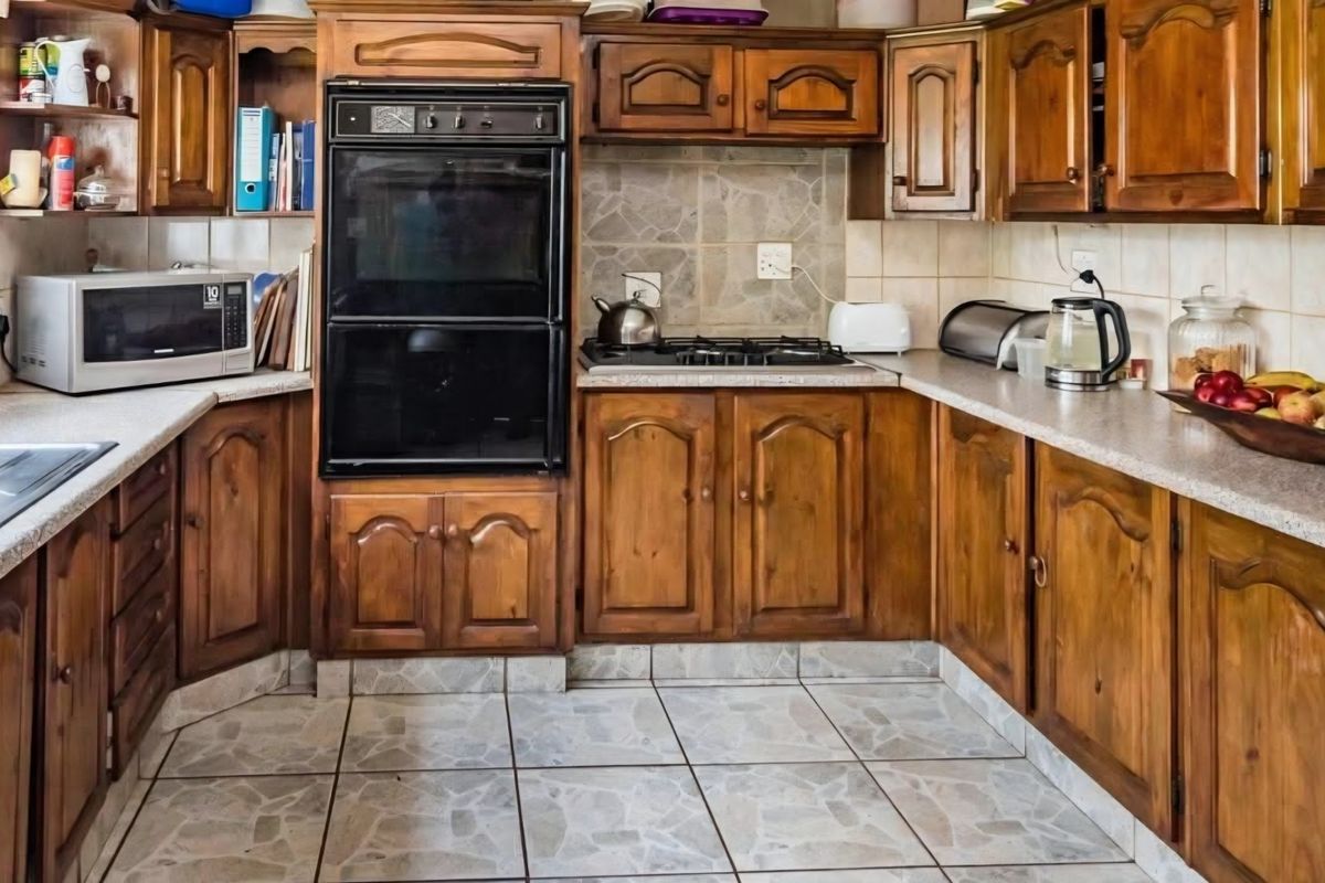 A functional kitchen featuring traditional wooden cabinetry, built-in oven, gas hob, and tiled finishes, offering a classic layout with ample storage space.