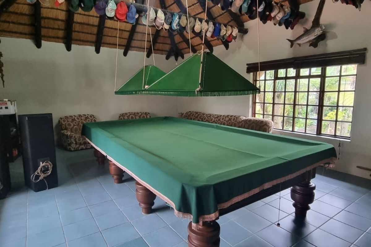 Spacious living area featuring a traditional thatched roof with exposed timber rafters, tiled flooring, and large windows providing natural light.