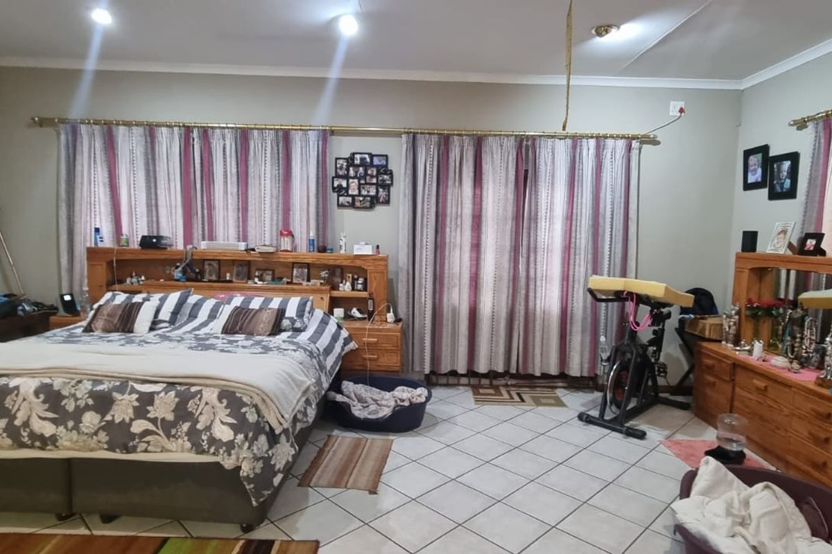 Spacious bedroom featuring ceramic tiled flooring, recessed downlighting, and a wall-mounted air conditioning unit.