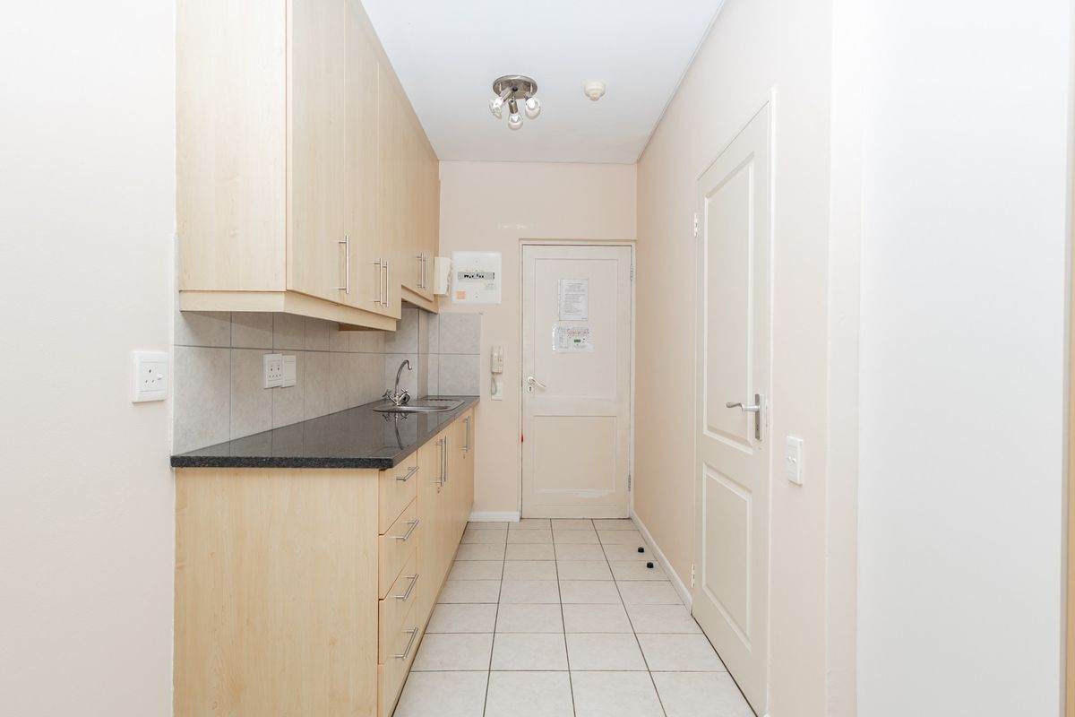 A functional kitchen area featuring light wood cabinetry, dark granite countertops, tiled flooring, and a tiled backsplash, providing a clean and practical workspace.