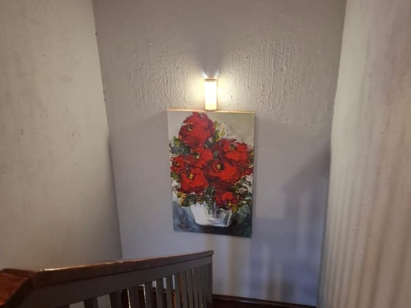A staircase landing area featuring a wooden handrail and a wall-mounted light fixture, providing access between levels.