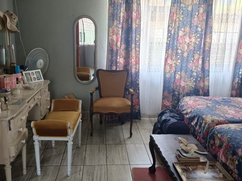 A bedroom featuring tiled flooring and a window with curtain rod fixtures.