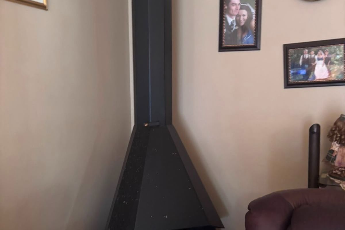 A corner living room space featuring a black metal freestanding fireplace with an integrated flue.