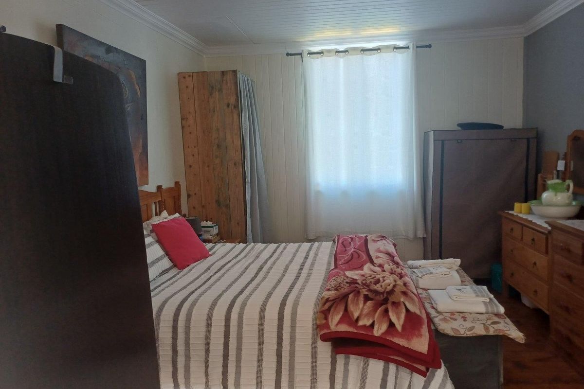 A cozy bedroom featuring timber panelled walls, a timber ceiling, and warm timber flooring, providing a rustic and comfortable atmosphere.
