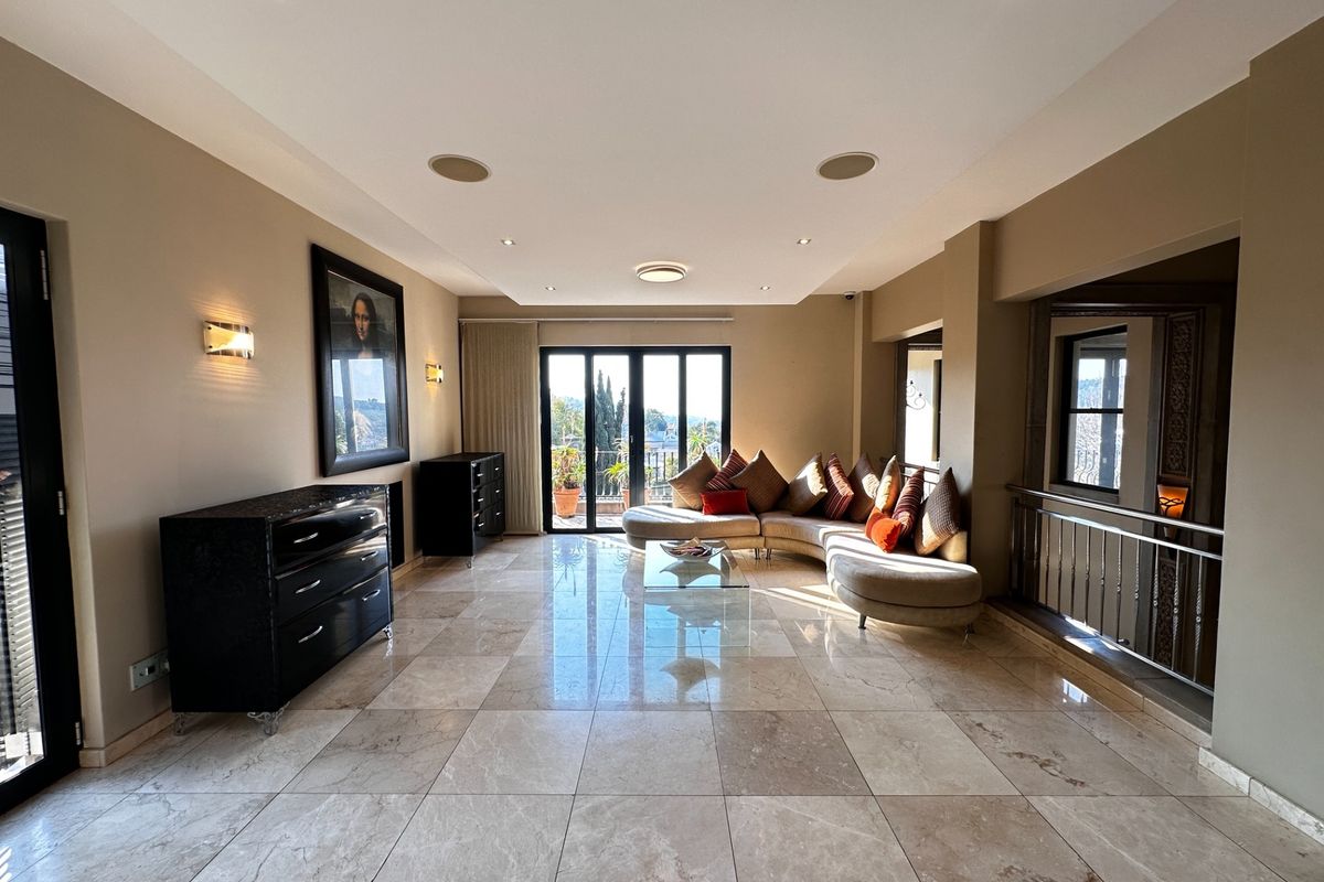 Spacious living room featuring polished marble flooring, recessed downlights, integrated ceiling speakers, and large sliding glass doors leading to an outdoor area.