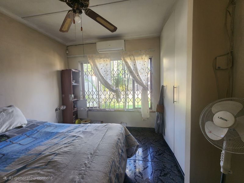 A bedroom featuring built-in cupboards, a ceiling fan, and a wall-mounted air conditioning unit, with security bars installed on the window.