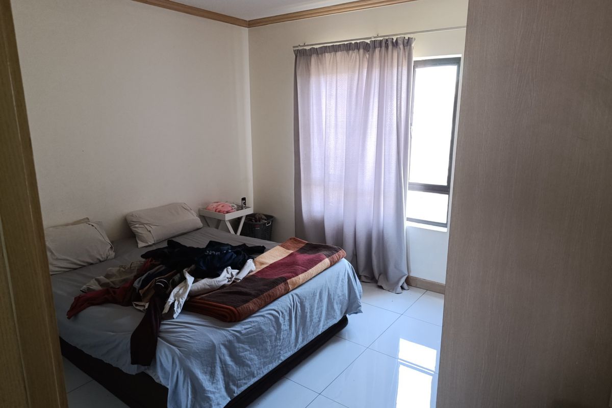 A standard bedroom featuring tiled flooring and a window with curtain rails, providing a functional living space.