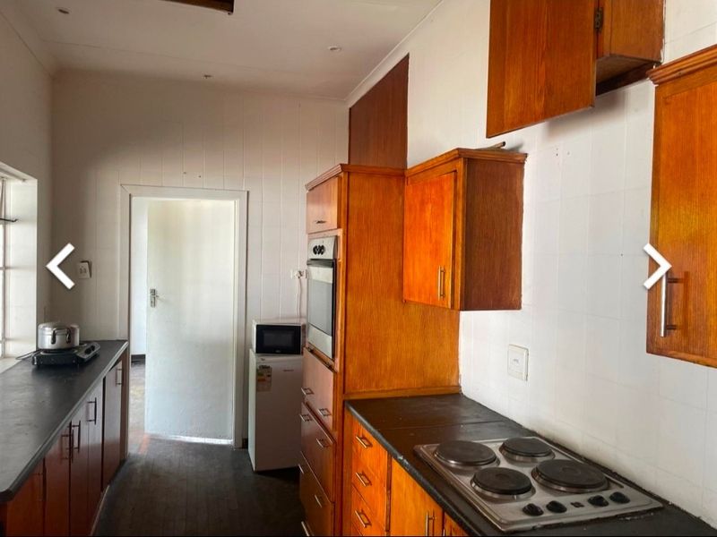 A dated kitchen featuring wooden cabinetry, built-in oven, electric hob, and tiled splashbacks, offering potential for a modern renovation.