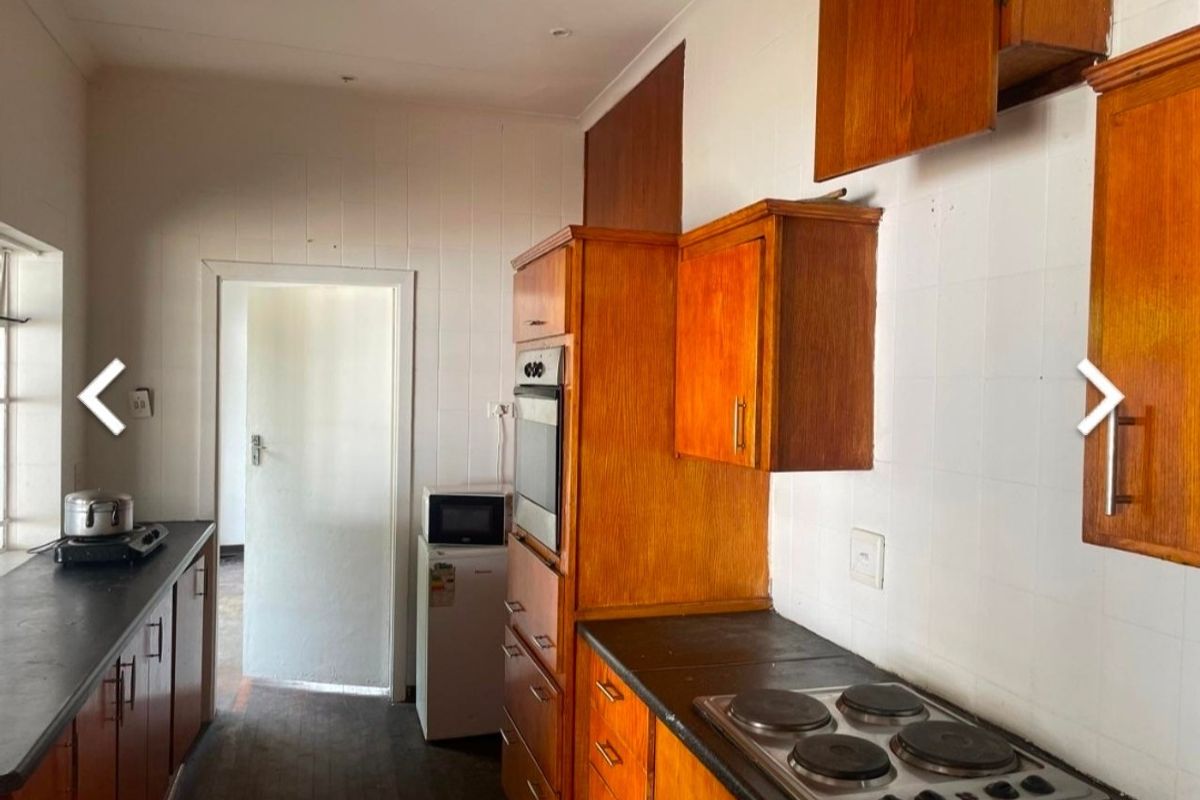 A dated kitchen featuring wooden cabinetry, built-in oven, electric hob, and tiled splashbacks, offering potential for a modern renovation.